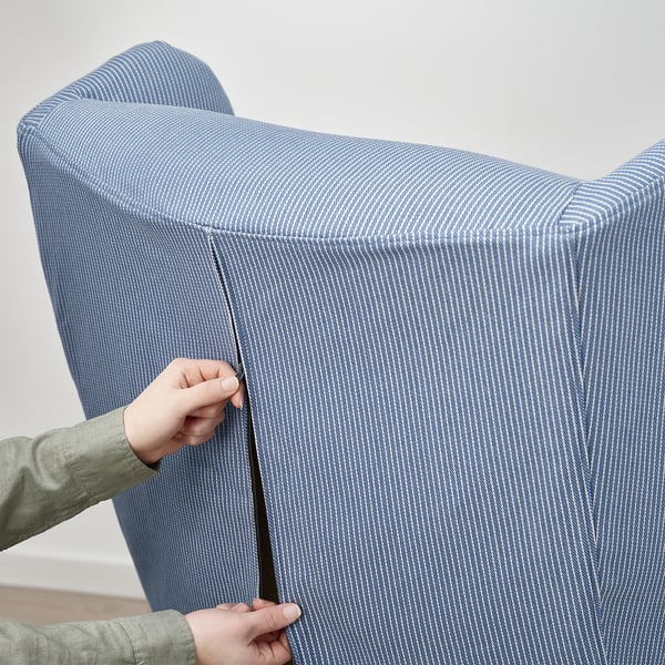 Inimene, kes asetab toolile sinise triibulise katte, mis näitab praktilist ja hõlpsasti kasutatavat disaini.