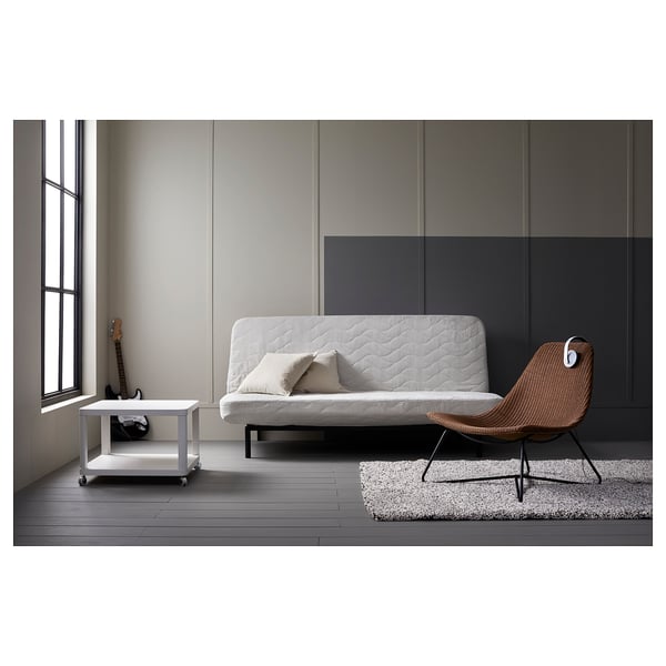 Moodne minimalistlik elutuba valge futoni, vitstest tooli ja valge ratastega lisalauaga.