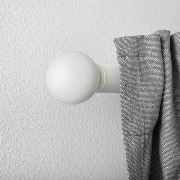 Valge sfääriline kardina lõpp, mis on kinnitatud halli kardina külge.