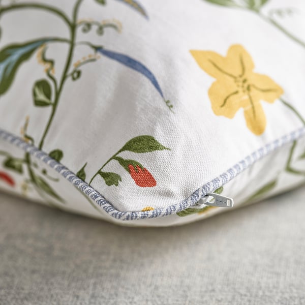 Zippered cushion cover with floral print and green piping.
