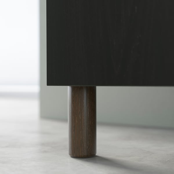 Black BESTÅ cabinet with cylindrical wooden leg.