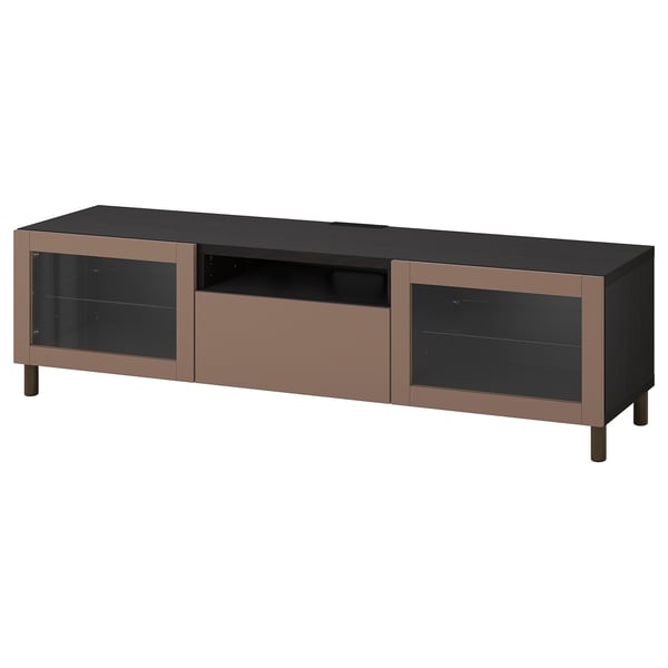 A modern BESTÅ tv stand in brown with glass doors and wooden legs, offering storage and cable management.