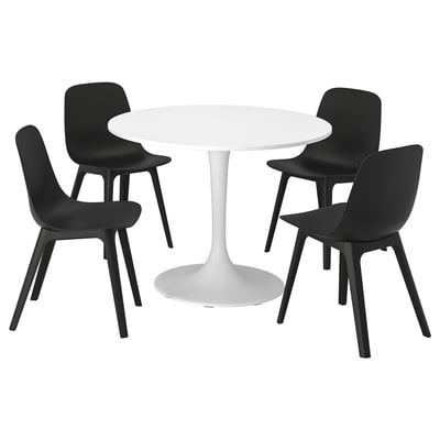 A white round dining table with four black stackable chairs. The table has a single pedestal base and the chairs have a modern, sleek design.