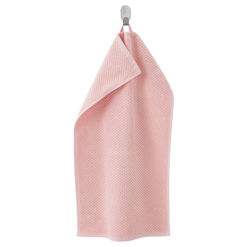 A light pink, soft cotton towel with a textured pattern hangs neatly on a metal hook.