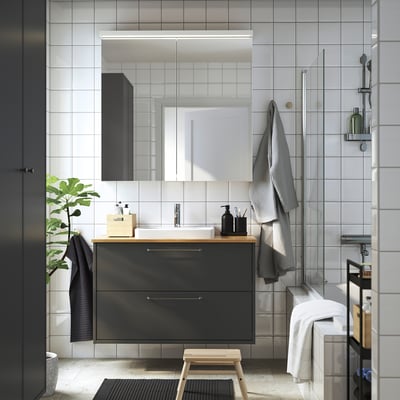 Modern bathroom featuring HAVBÄCK dark grey vanity with wood countertop, including sink and mirror. Size proportional to towels and plant.