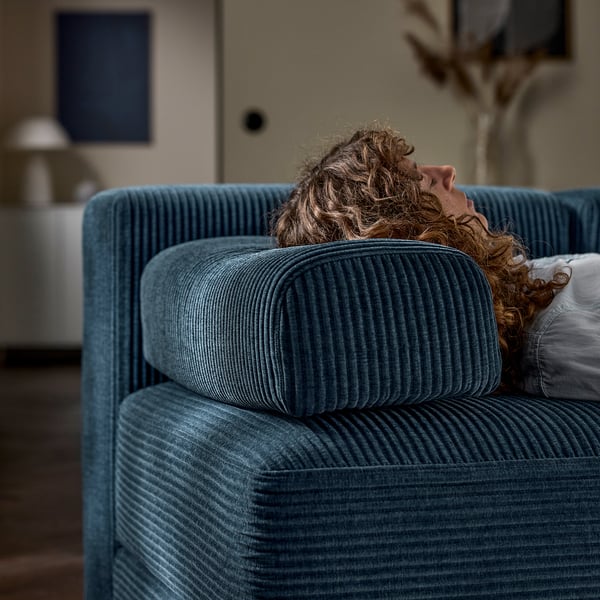 Person resting on a JÄTTEBO sofa, showcasing its comfortable, supportive cushions and storage feature.