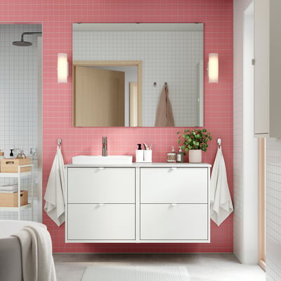 Modern bathroom with white vanity, pink tiles, mirror, lights, white towels.
