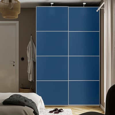 Large blue sliding closet, modern design, fits well in bedroom, sits next to bed.
