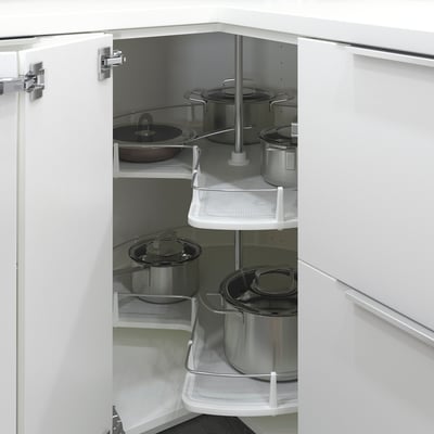 White kitchen cabinet with rotating shelves holding pots and pans.