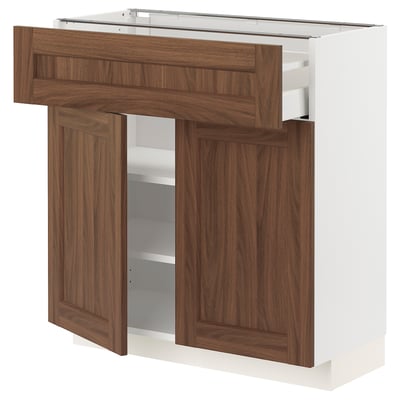 A METOD kitchen unit with walnut wood-effect doors and a white frame. It includes drawers and shelves for storage.