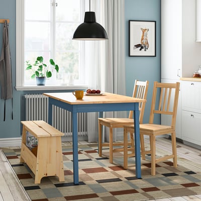 Modern dining area with PINNTORP table, chairs, bench, and fox print. Multi-colored rug, large window, black pendant lamp.
