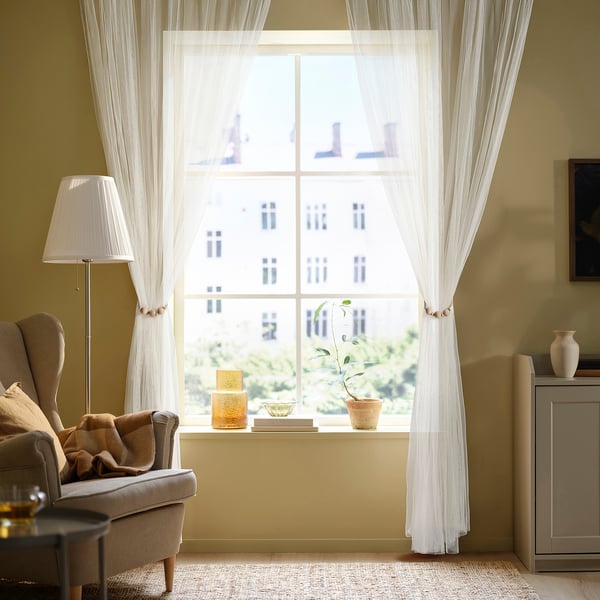 Living room with large window, armchair, side table, plant, and lamp.
