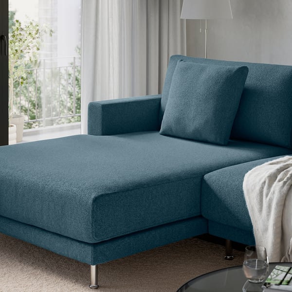 Modern blue sectional sofa with clean lines, plush cushions, and metallic legs, positioned near a large window with curtains.