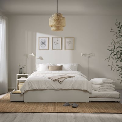 Minimalist white bed set, with matching storage boxes and hanging light. Two art frames above.