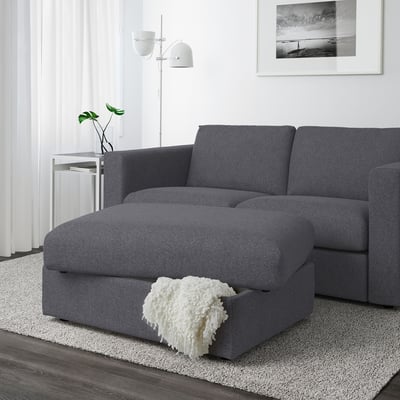 Modern living room with grey sectional sofa and storage footstool. Nagging under seat, cosy throw blanket.
