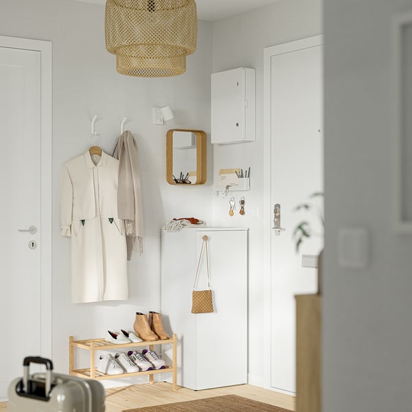 Entrada minimalista amb vestit beix, mocada, sabatera, armari, mirall, llum penjant i prestatgeria de claus.