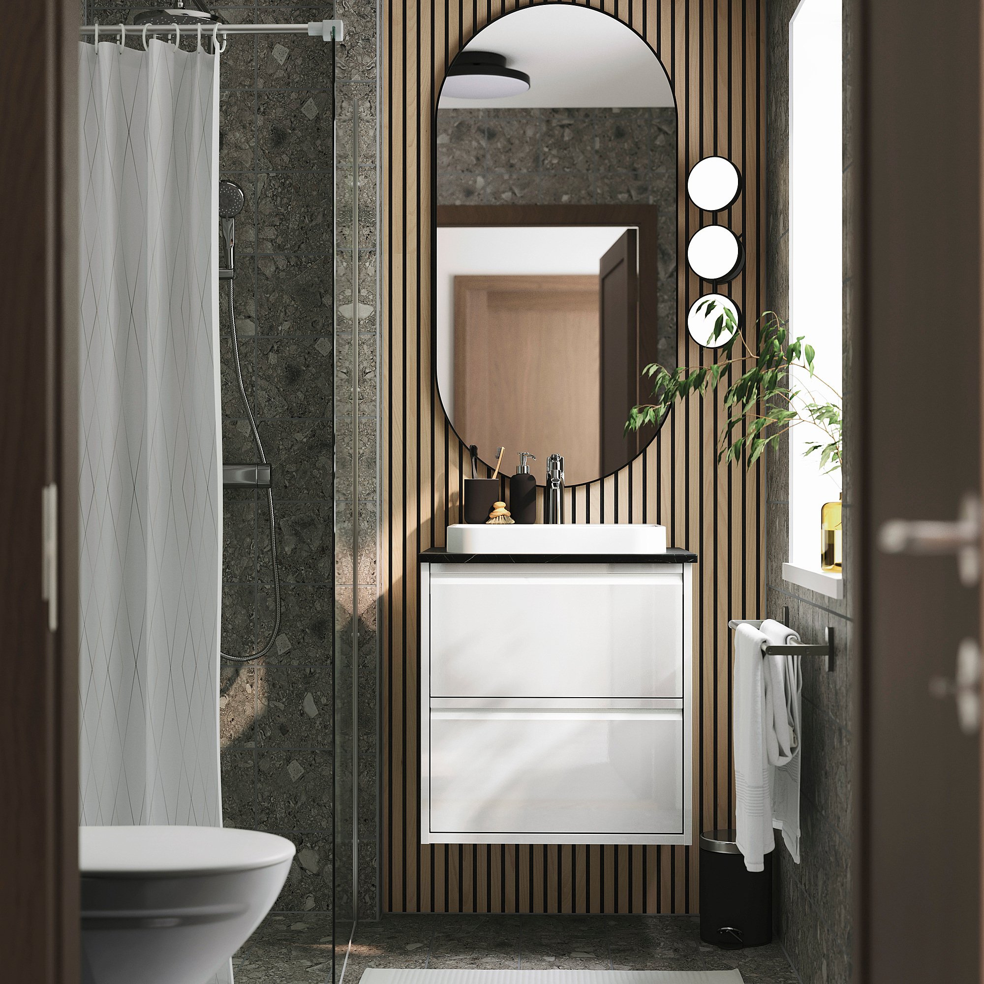 Bany modern amb lavabo ÄNGSJÖN blanc, mirall rodó, cortina de dutxa verda i planta en test.