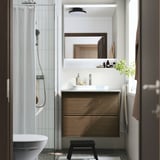 Bany modern: lavabo de fusta marró, taulell blanc, mirall; elegant, minimalista.