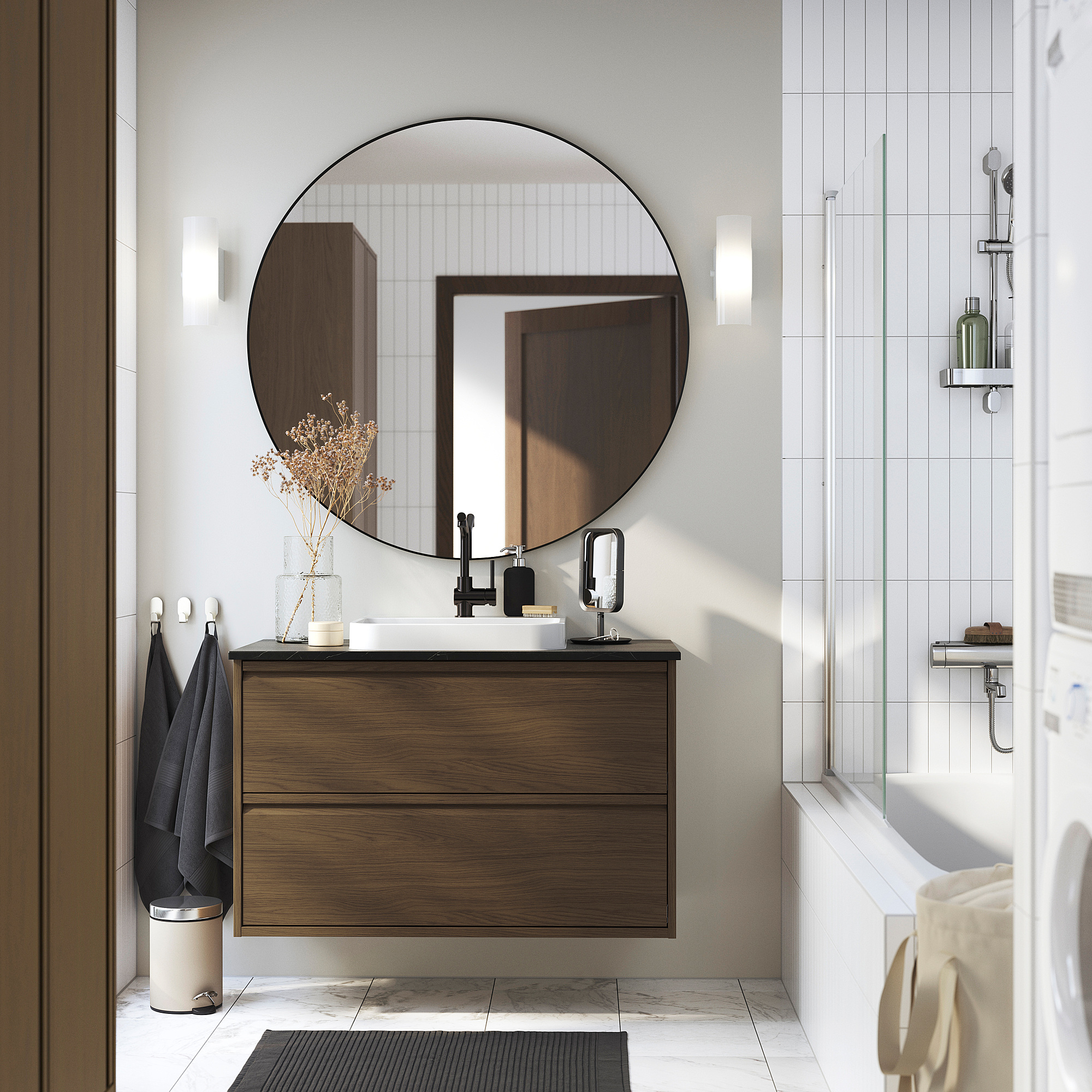 Bany modern amb armari de noguera ÄNGSJÖN, taulell blanc i lavabo; Gran mirall rodó, muntat a la paret per a una sensació d'amplitud.