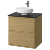 Un tocador de bany modern de roure amb taulell negre i lavabo blanc rodó. Es tracta de dos calaixos i un disseny de paret.