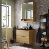 Bany modern amb tocador de fusta clara, lavabo de marbre, armari de miralls, parets verdes i detalls negres. Espaiós però acollidor.