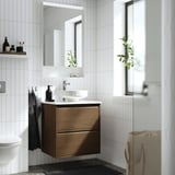Bany modern: elegant armari de noguera, lavabo blanc, mirall gran, plantes.