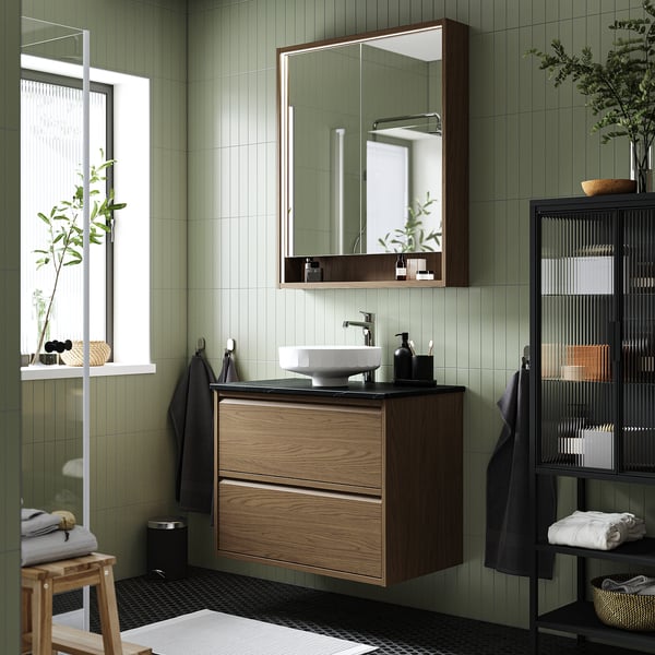 Configuració moderna del bany: moble ÄNGSJÖN en roure marró, lavabo central rodó, mirall, plantes, tovalloles, estil minimalista.