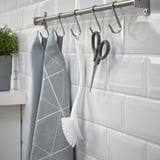 Bastidor metàl·lic amb ganxos que subjecten eines de cuina: tela, raspall, tisores.
