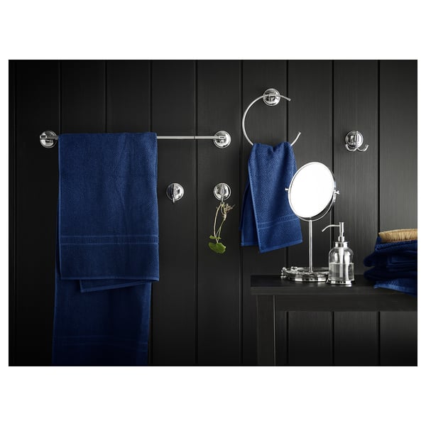 Bany negre modern amb accessoris cromats, tovalloles blaves i mirall.