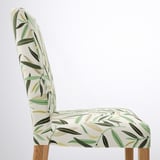 Cadira elegant amb respatller alt amb estampat de fulles verdes, respatller corbat, seient encoixinat i potes de fusta. Disseny modern, teixit ecològic.