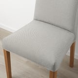Primer pla d'una cadira entapissada moderna amb potes de fusta, amb un teixit d'alta qualitat i un disseny còmode.