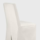 Una cadira entapissada moderna i blanca amb línies elegants i un respatller alt, que ofereix una experiència de seient elegant i còmoda.