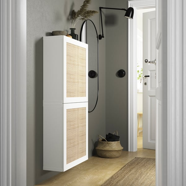 Passadís modern amb armari alt BESTÅ en blanc, portes amb textura, al costat de cistella i llum.