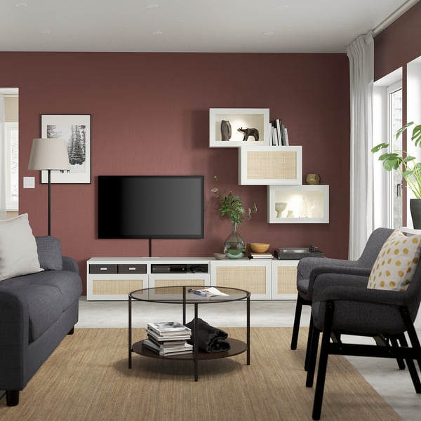 Sala d'estar moderna amb parets vermelles fosques, mobles grisos, tv, butaques. Plantes decoratives, ambient acollidor.