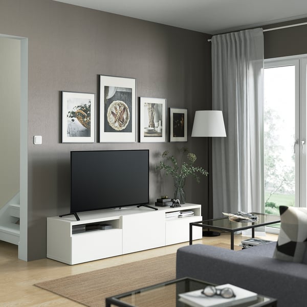 Sala d'estar moderna amb banc de TV BESTÅ, taula de centre de vidre, sofà gris i gran finestral.