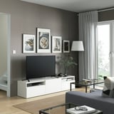 Sala d'estar moderna amb banc de TV BESTÅ, taula de centre de vidre, sofà gris i gran finestral.