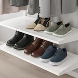 Les prestatgeries blanques mostren calçat divers: talons, mocassins, botes i sabatilles esportives ben organitzades. Ideal per a diverses estacions i clima.