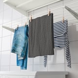 Tres peces pengen al sistema de paret BOAXEL: texans blau clar, camisa de ratlles blanques i negres i camisa de ratlles blaves i blanques.