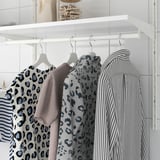 Armari amb camises penjants: estampat de lleopard, gris massís, ratlles. Barana blanca, prestatgeries, ganxos.