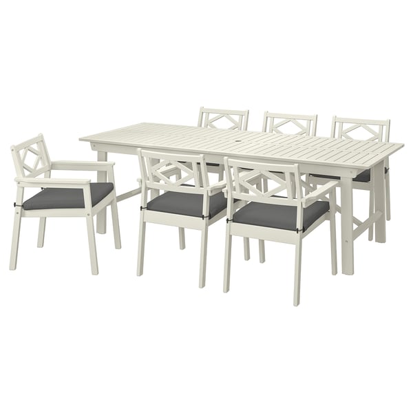 Conjunt de menjador exterior blanc amb taula rectangular i sis butaques, amb coixins foscos. Fabricat en fusta d'acàcia i plàstic.