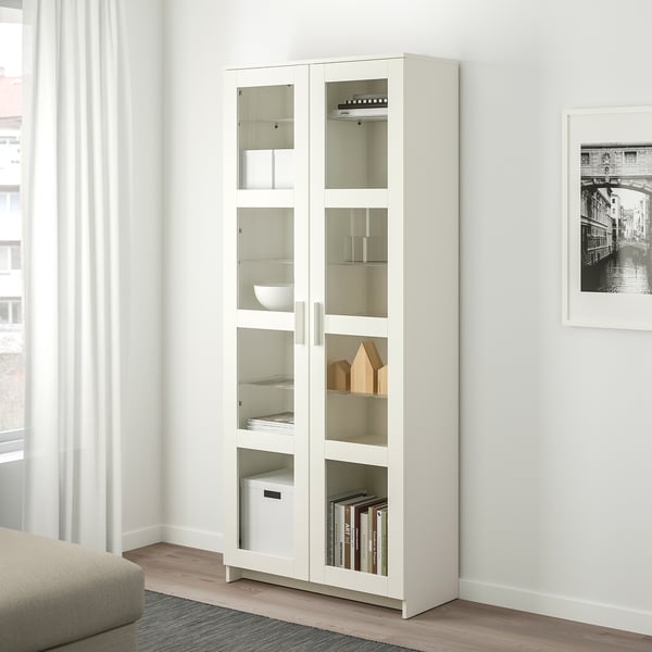 Armari blanc BRIMNES amb portes de vidre. El disseny alt, prim i modern s'adapta als llibres, la decoració. La prestatgeria mostra els articles amb claredat mentre els protegeix.