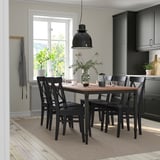 Conjunt de menjador negre DANDERYD amb taula, sis cadires, gerro i tasses a l'habitació moderna.