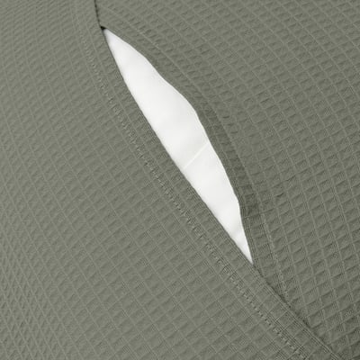 Primer pla d'una funda de coixí gris-verd amb tancament de sobre, que mostra el seu patró de gofres amb textura.