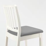Una cadira de fusta blanca amb seient encoixinat gris, elegant i còmoda.
