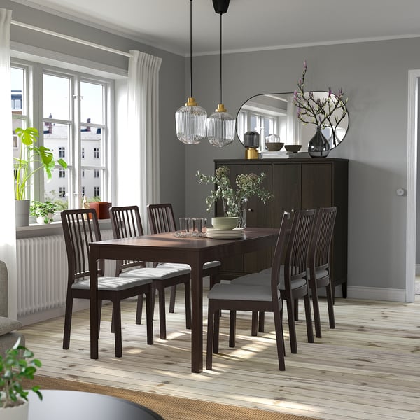 Conjunt de menjador modern amb taula extensible, sis cadires i armari de fusta fosca, elegantment col·locat contra parets grises clares, amb llums penjants a sobre.