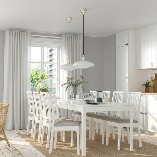 Conjunt de menjador modern amb taula extensible, cadires grises, 3 penjolls i gran finestral.