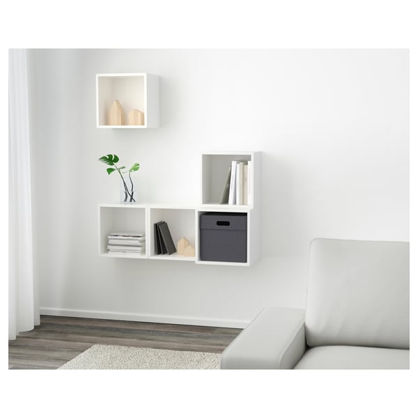 Prestatgeries de paret blanques amb compartiments per a llibres i decoració, disposades asimètricament.