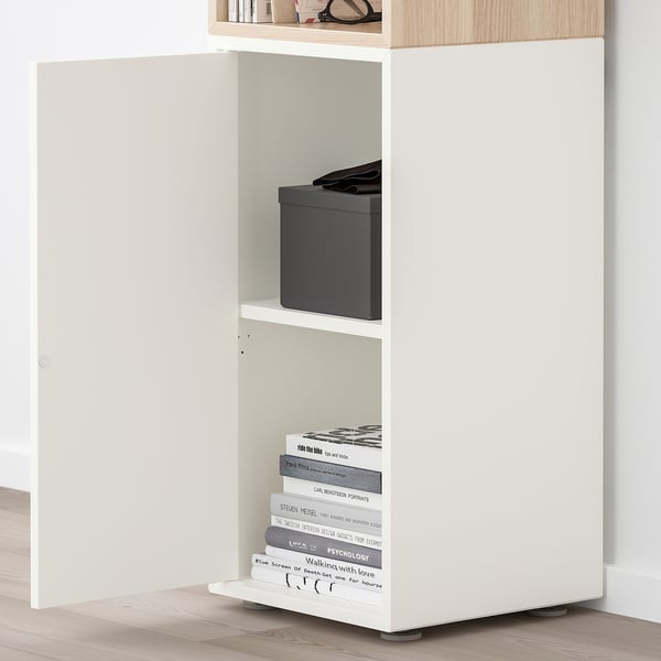 Prestatge EKET blanc, ajustable, fixat a la paret amb llibres i caixa.