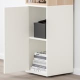 Prestatge EKET blanc, ajustable, fixat a la paret amb llibres i caixa.