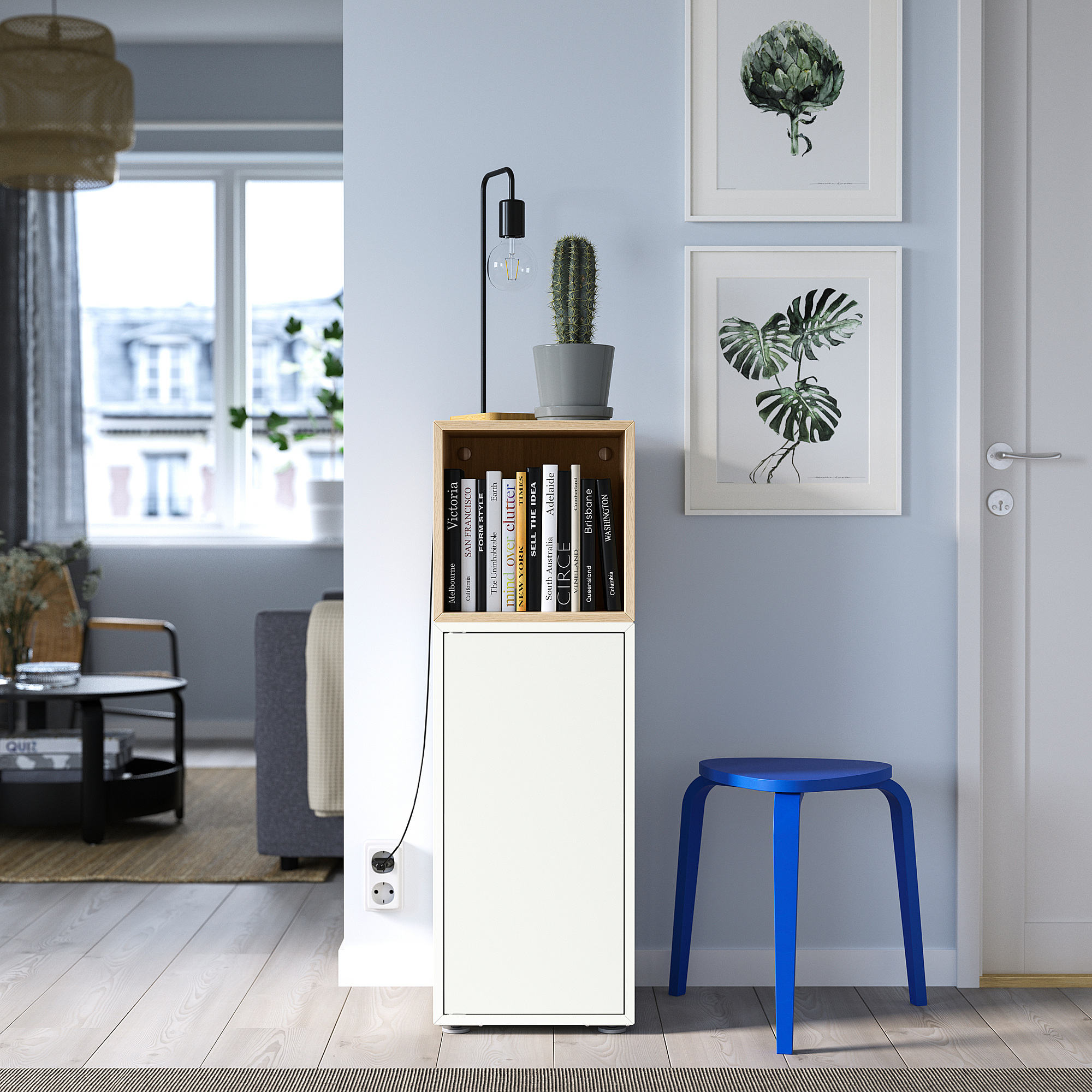 Sala d'estar moderna amb armari EKET, llibres, cactus, tamboret blau, estampats i seients acollidors.